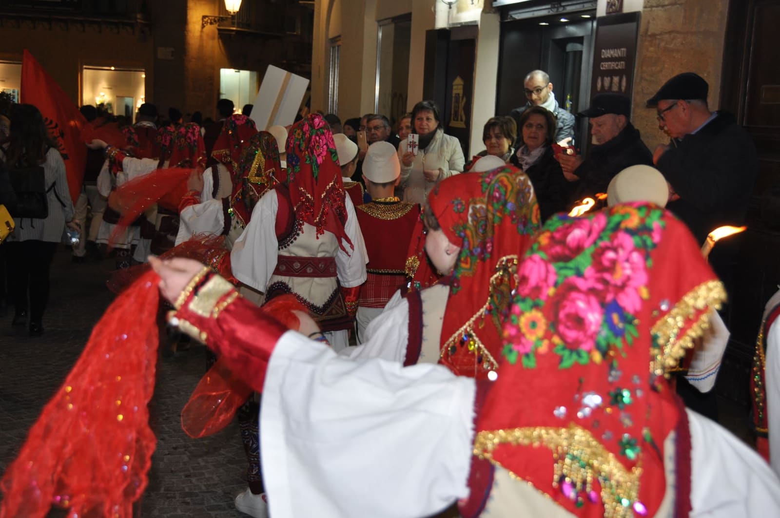 un gruppo in costume rosso e bianco sfila per le strade del centro durante la sagra del Mandorlo in fiore