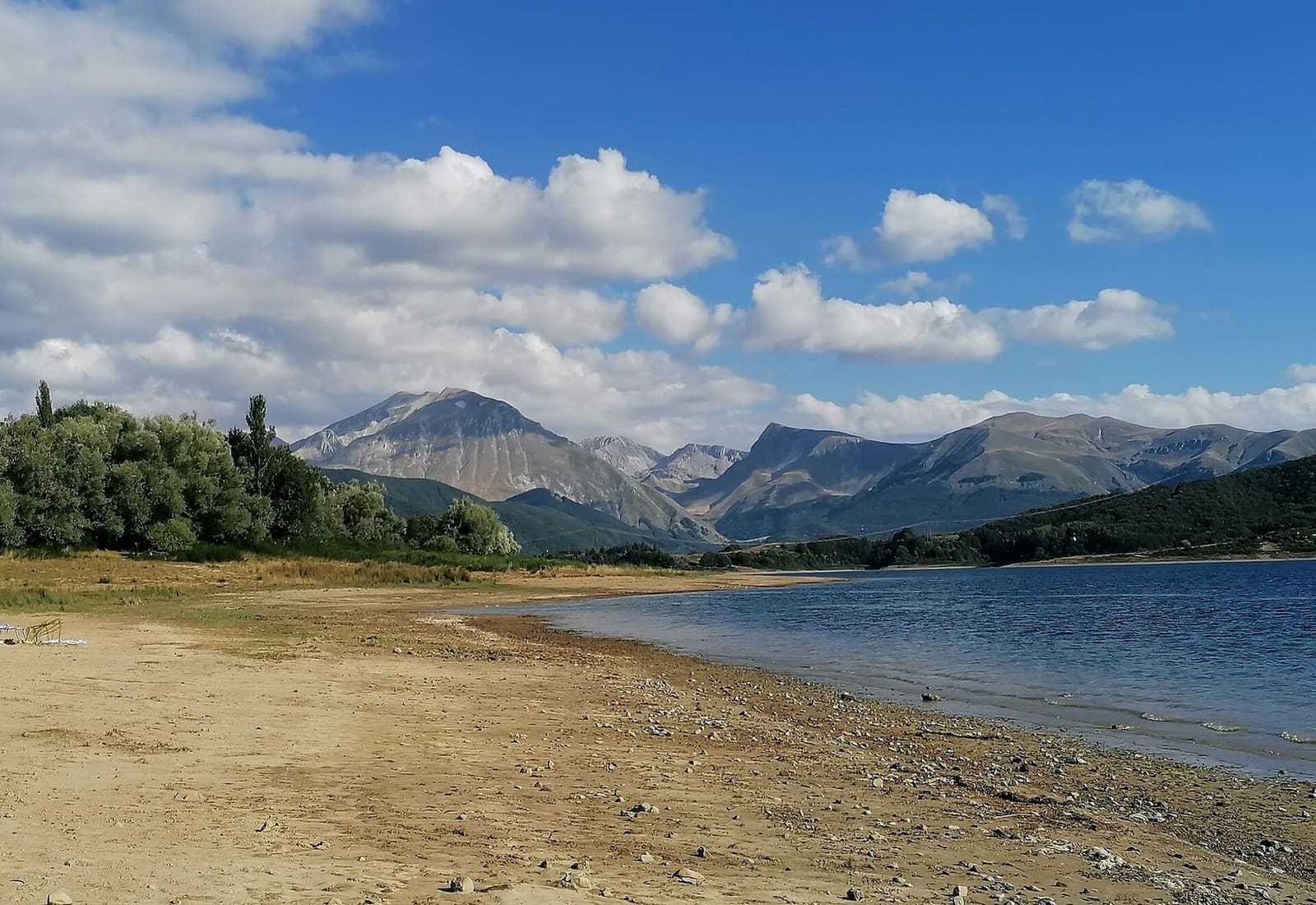 das Ufer aus Kies und Sand am Lago di Campotosto, mit den Bergen im Hintergrund