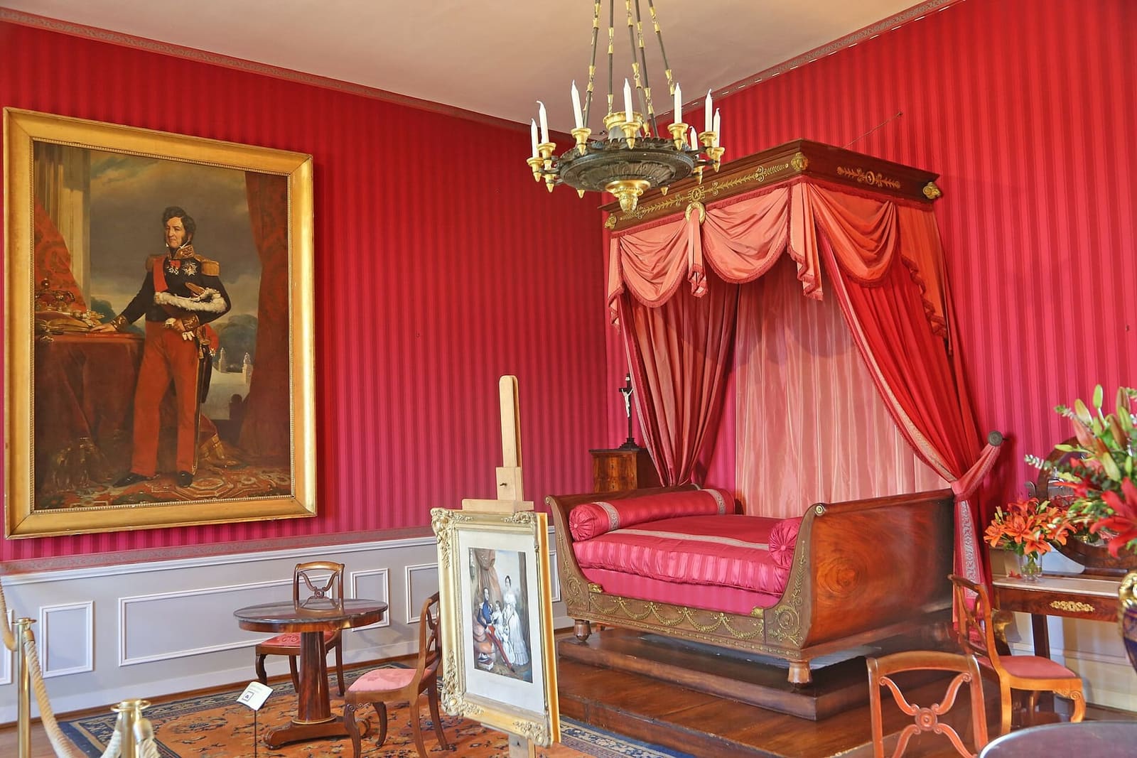 a nineteenth-century bedroom in the château, with red walls and a canopy bed
