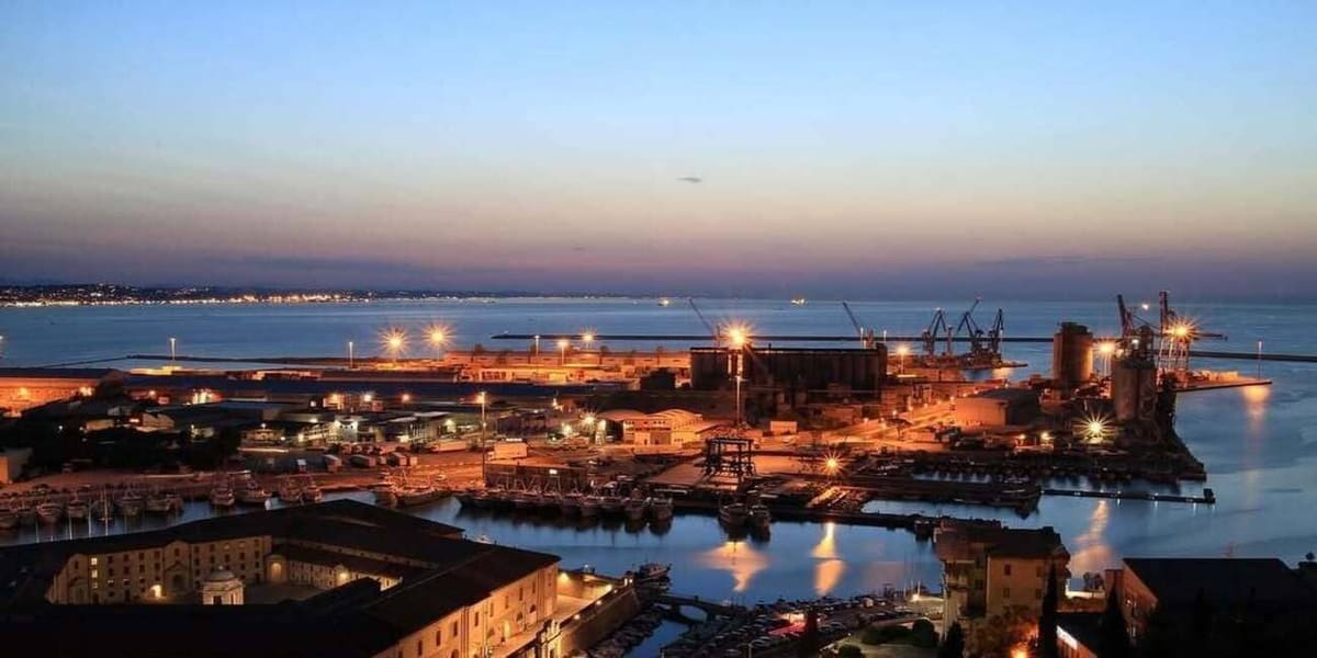 il porto di Ancona al crepuscolo visto dall'alto, con le banchine illuminate e la costa in fondo