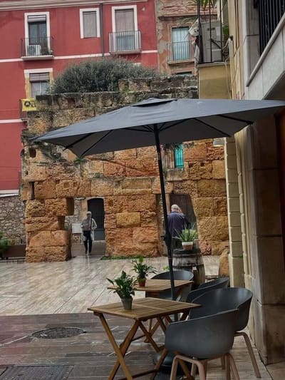 i tavolini di un bar addossati a un muro romano, dopo la pioggia
