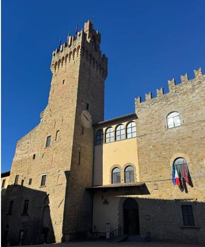 la torre merlata del palazzo comunale, con l'orologio e le bandiere