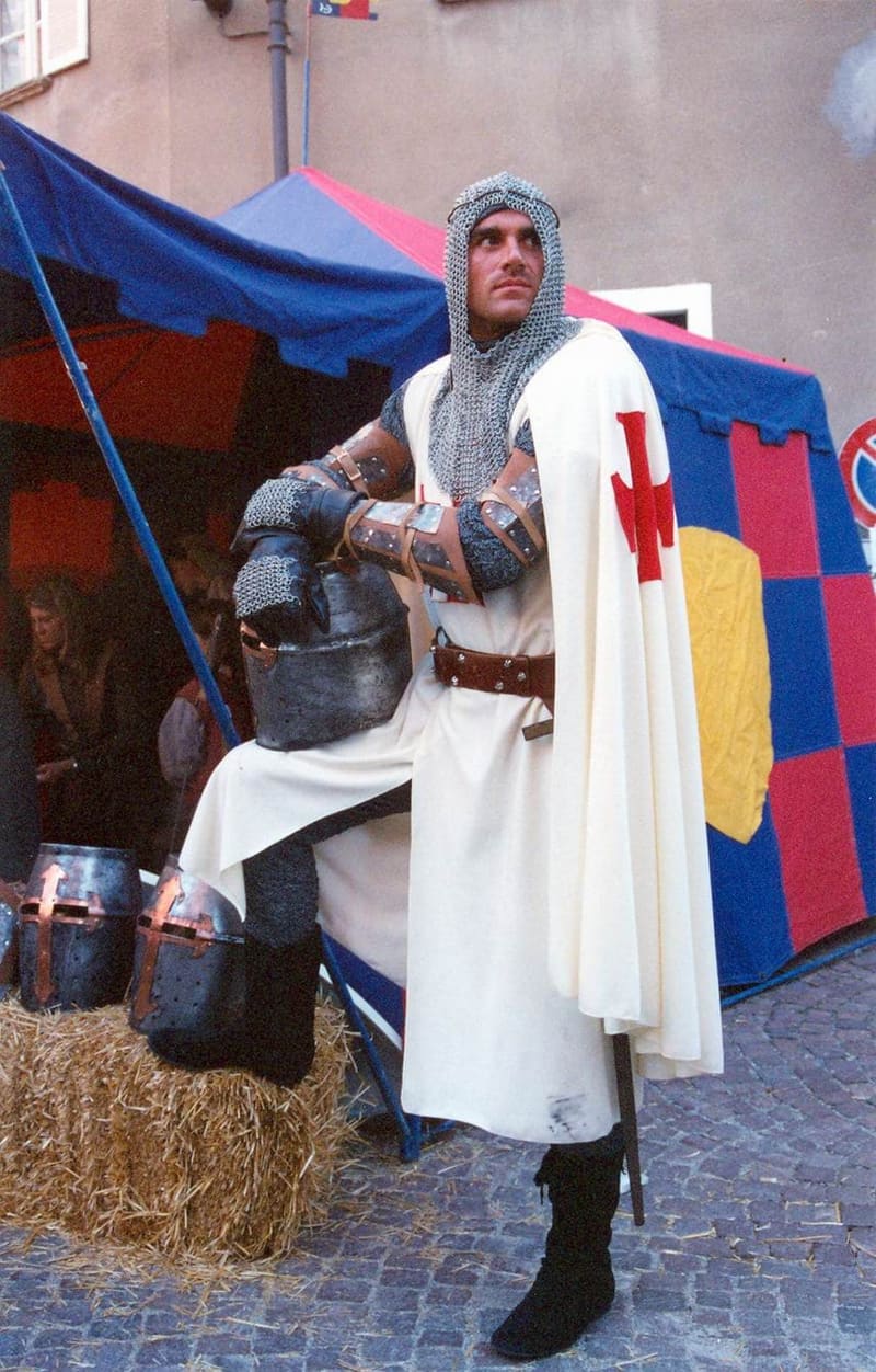 a costumed figure in armour in front of the tent of a borgo, at the Palio of Alba in October 2004