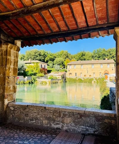 la vasca inquadrata da sotto il loggiato, con le travi e i coppi del tetto