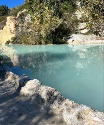 l'acqua turchese e lattiginosa di una vasca libera, fra le rocce bianche di travertino