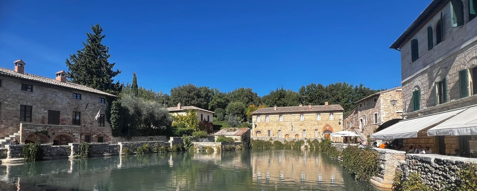 la vasca di acqua termale che occupa la piazza, con i palazzi in pietra intorno
