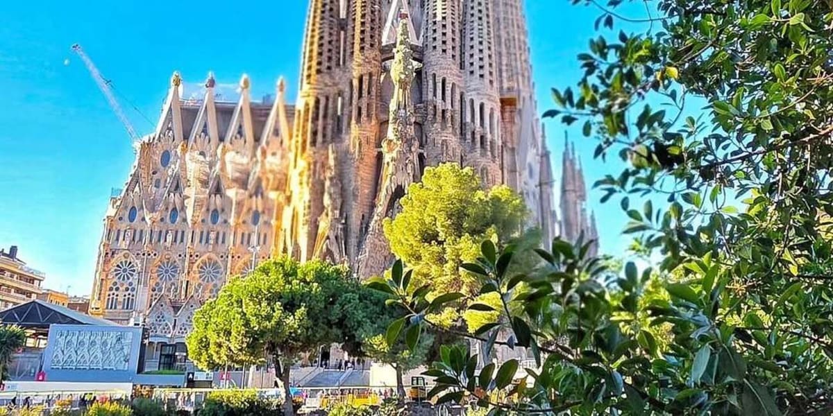 la Sagrada Família che spunta sopra gli alberi del parco, con la gru del cantiere a sinistra
