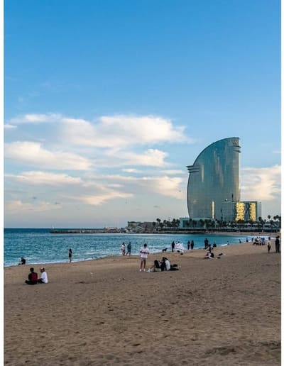 la spiaggia della Barceloneta nel tardo pomeriggio, con la vela dell'hotel W in fondo