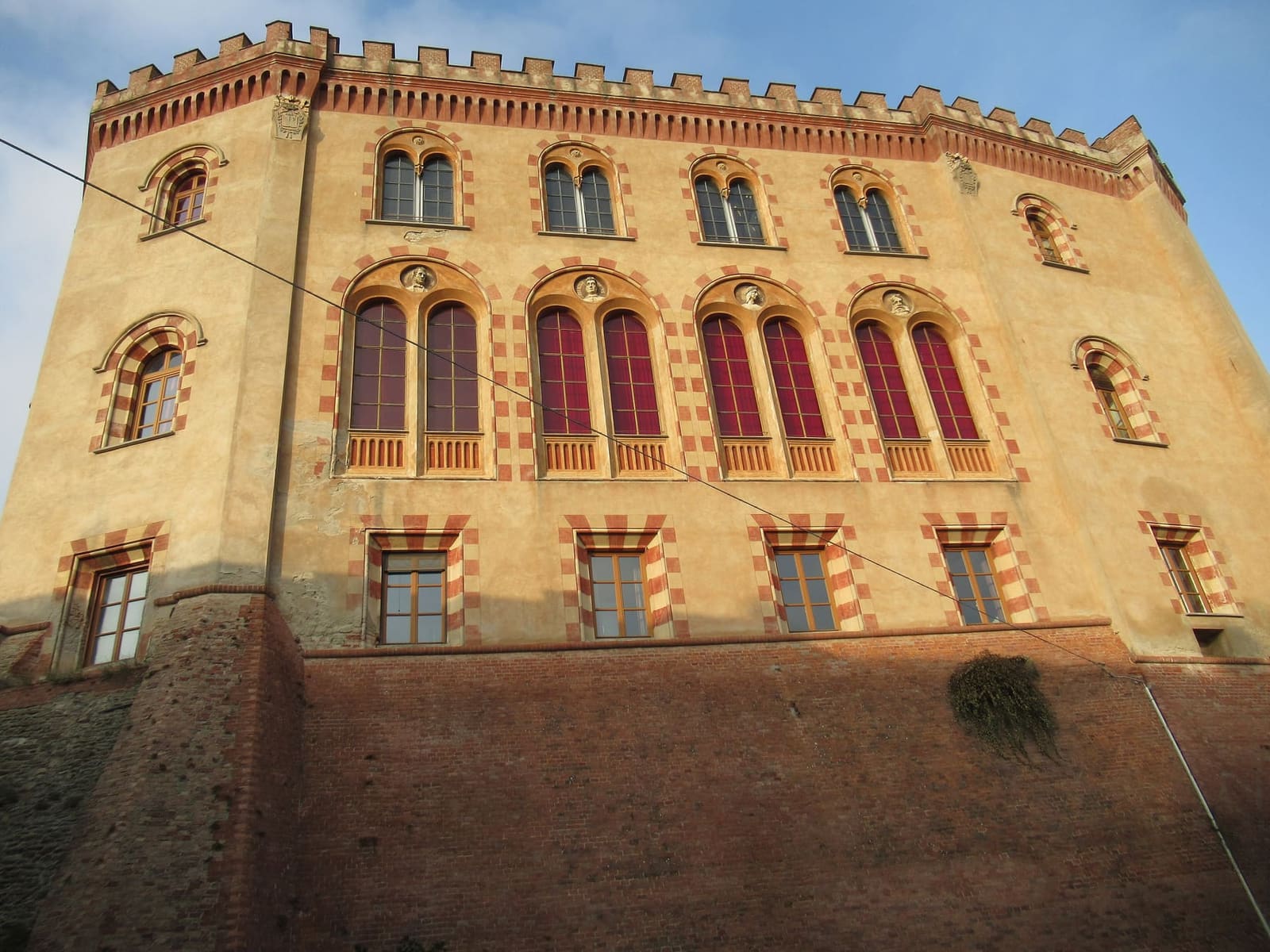 la facciata lunga del castello nella luce del tramonto, con le finestre bifore e i merli