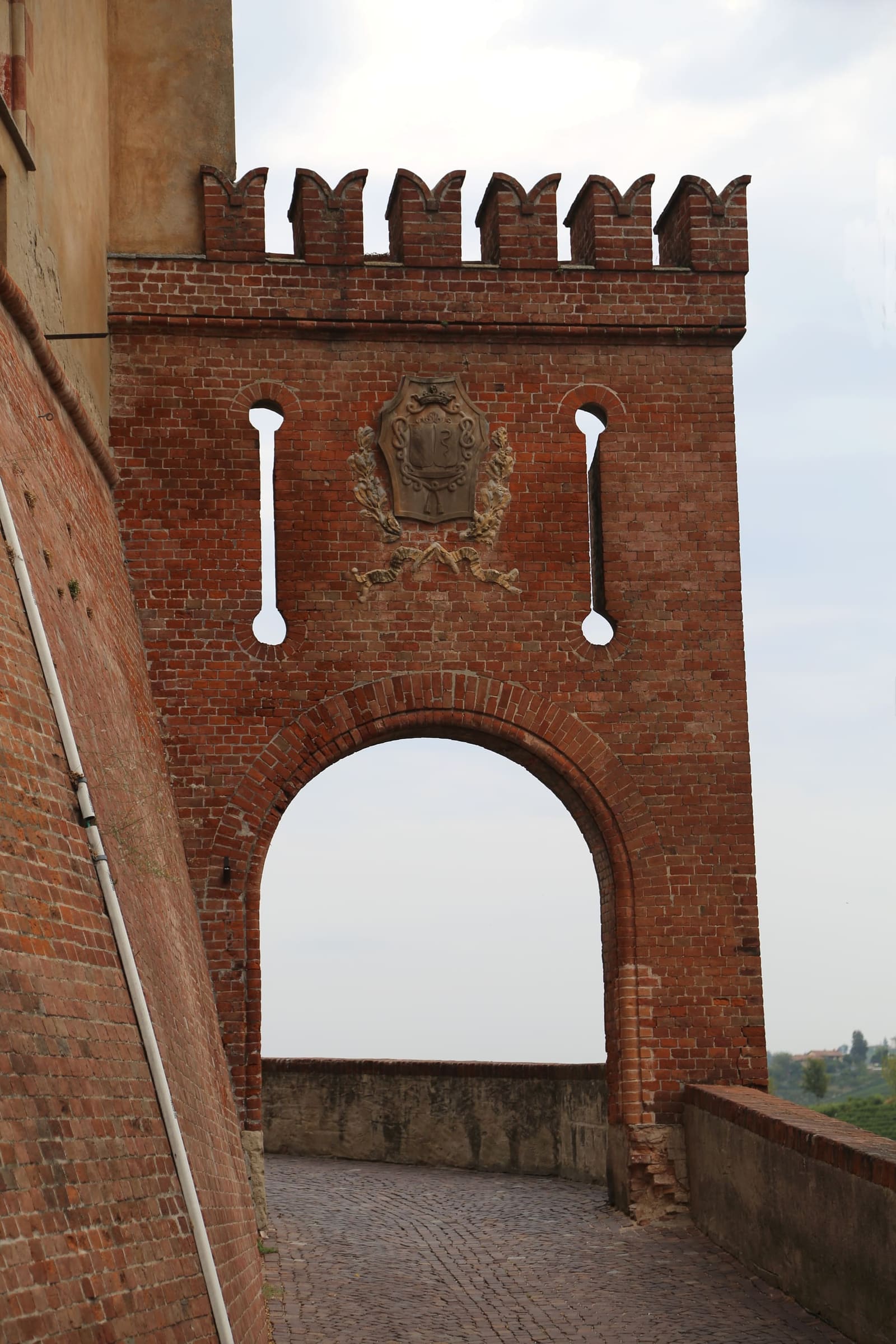 la porta merlata di mattoni accanto al castello, aperta sul vuoto delle colline