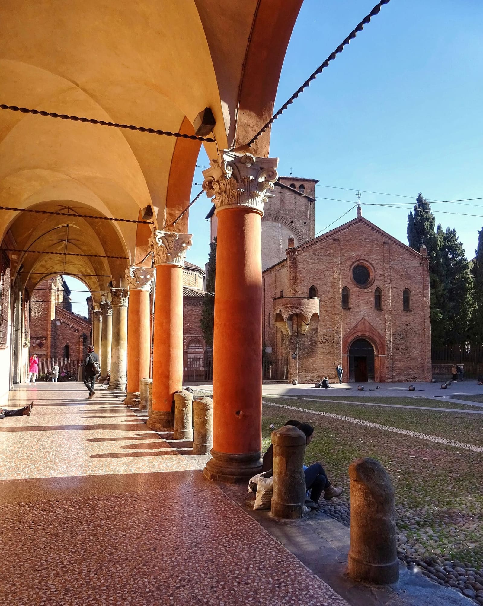 il portico su piazza Santo Stefano, con la basilica in fondo, in un pomeriggio di febbraio