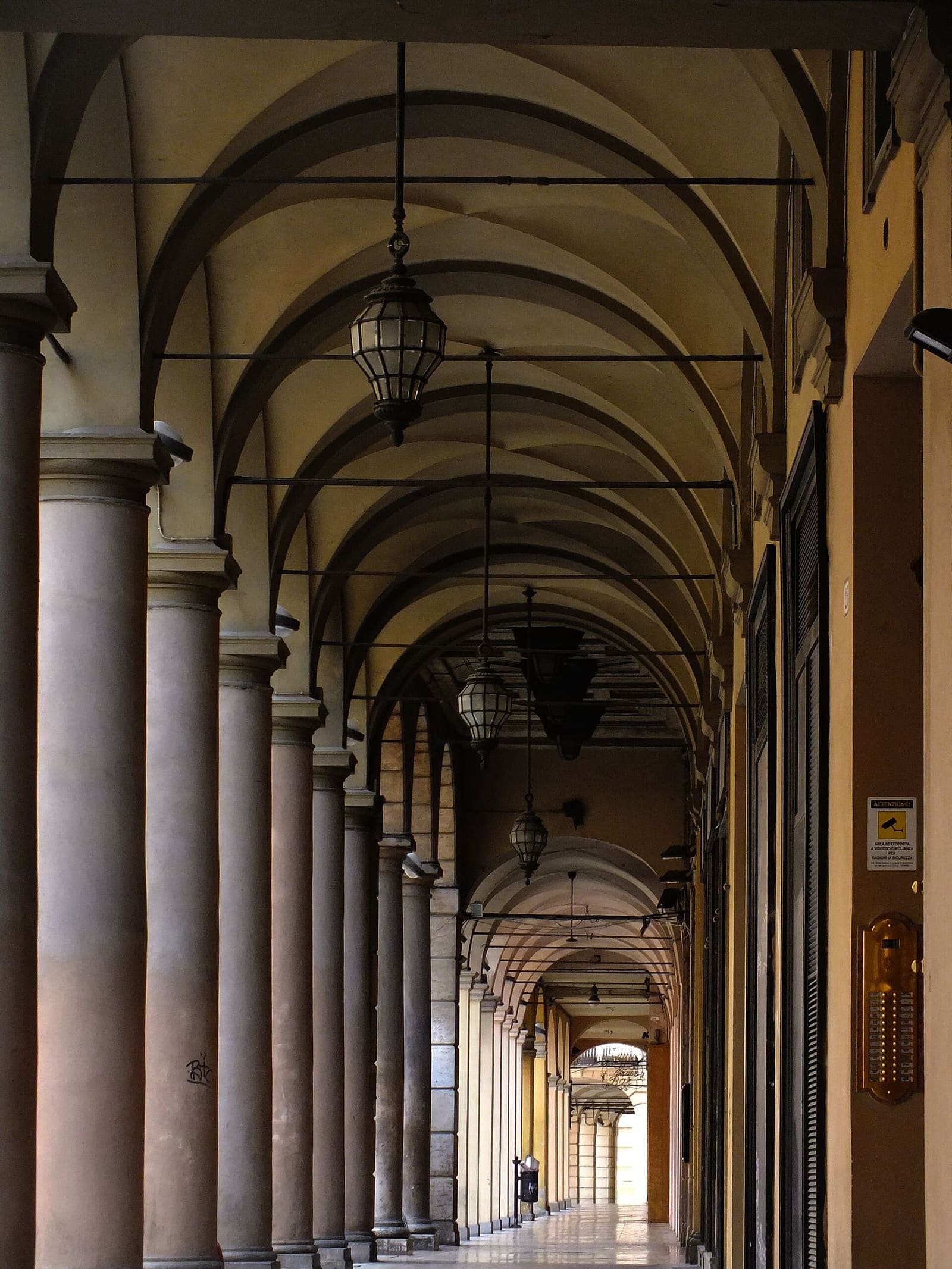 un portico del centro di Bologna, con le volte a crociera e i lampioni appesi