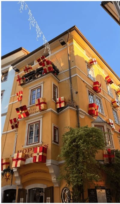 una casa gialla del centro con i finti pacchi regalo appesi alle finestre, di giorno