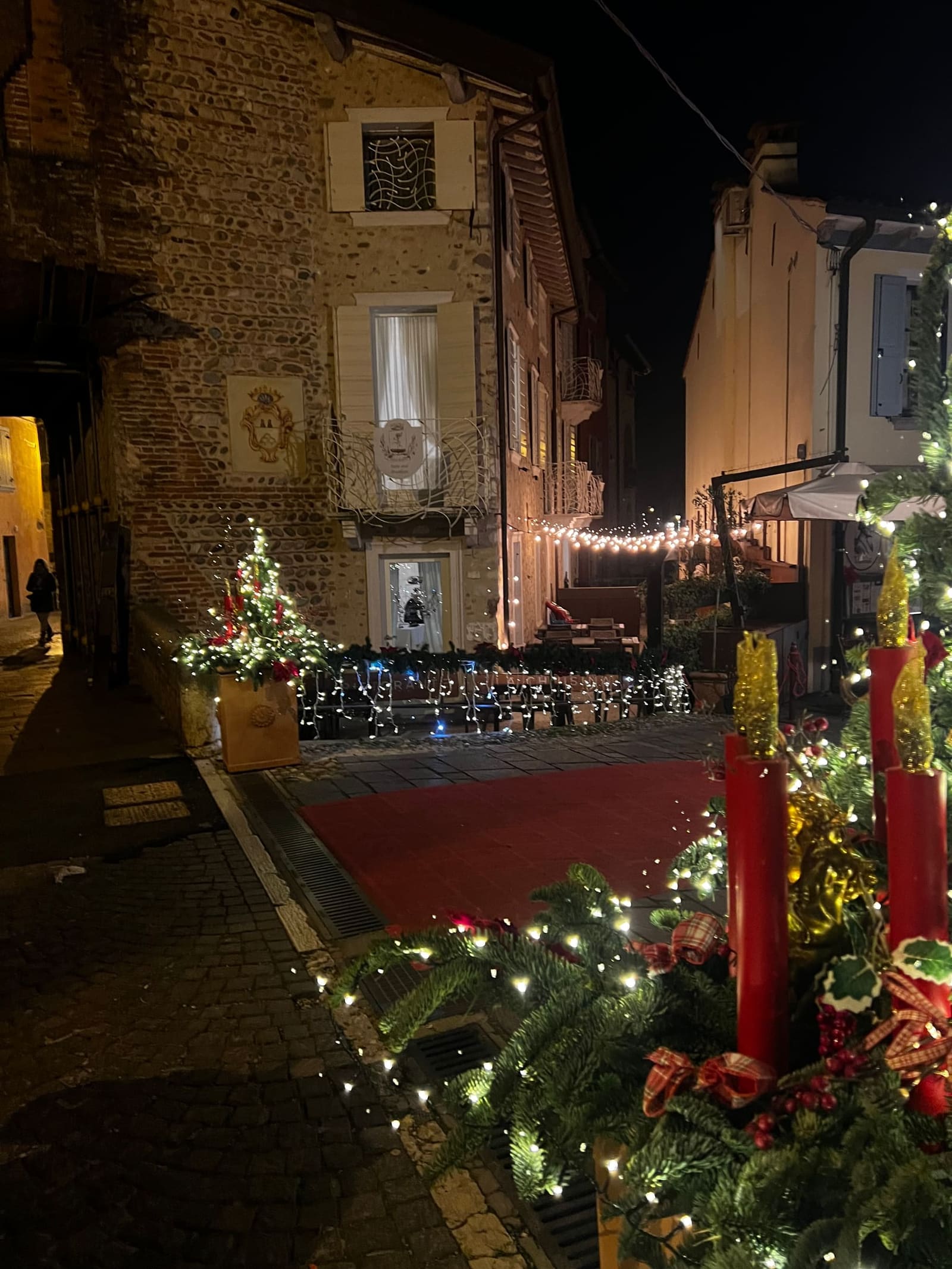 il vicolo del borgo addobbato per Natale, gli alberelli accesi e le candele rosse