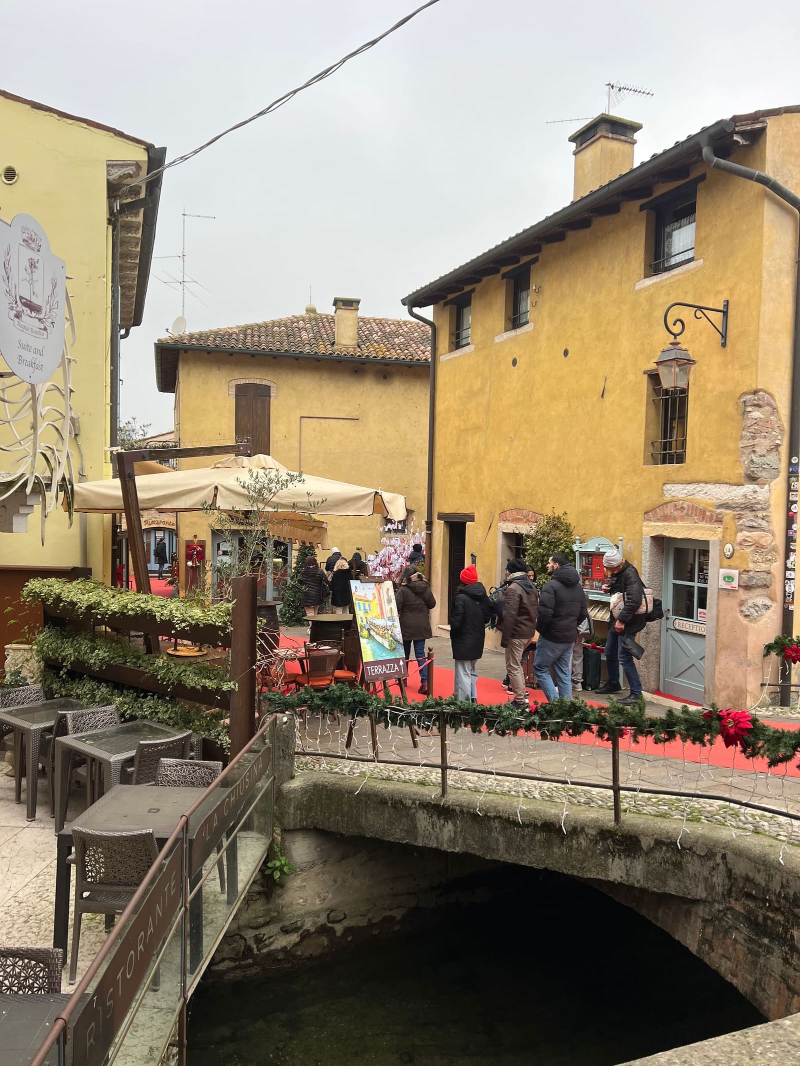 le case gialle sul canale e il tappeto rosso degli addobbi, dal ponticello del borgo