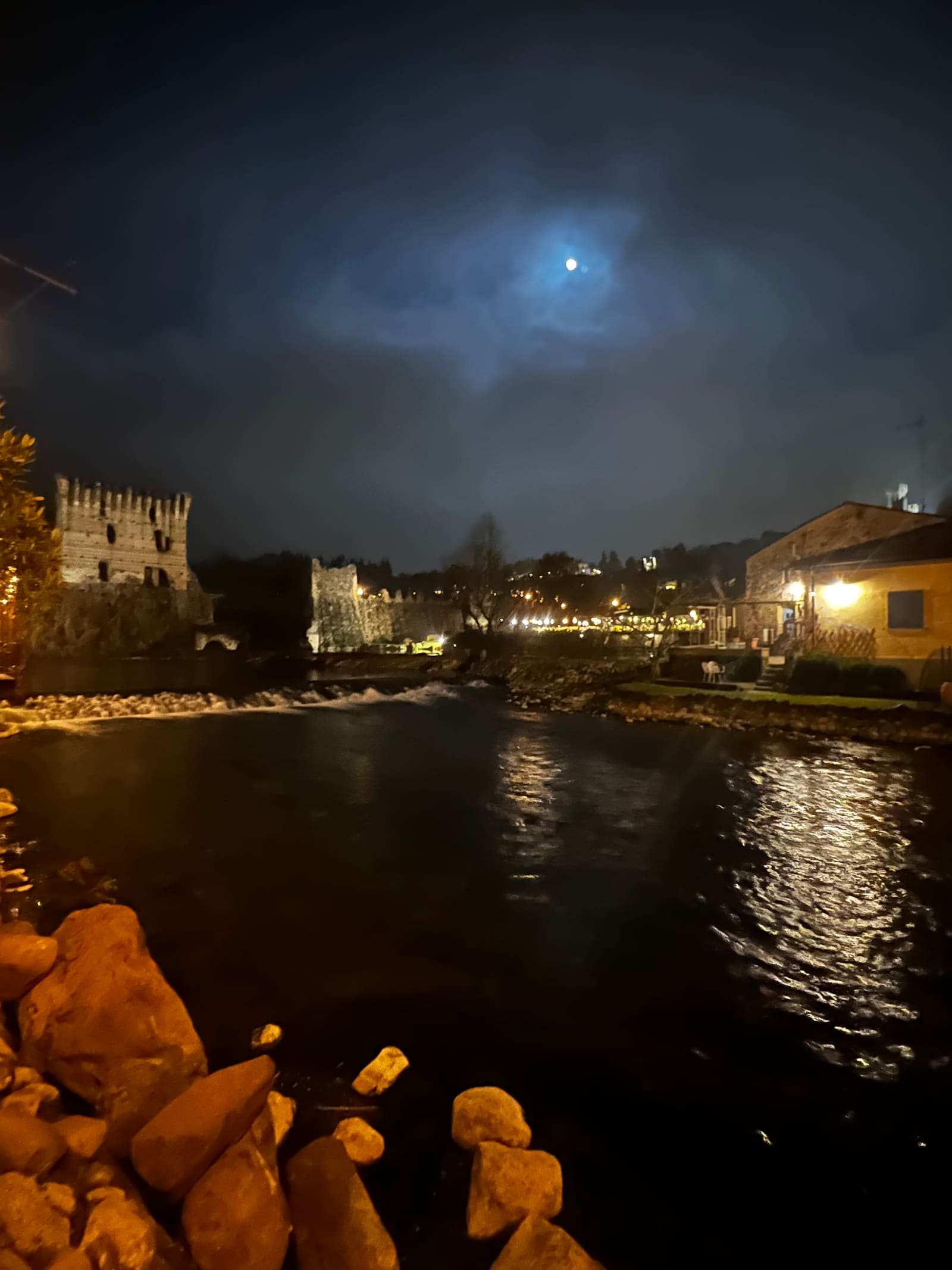 il Mincio di notte con la luna fra le nuvole, la torre del Ponte Visconteo a sinistra e il salto d'acqua
