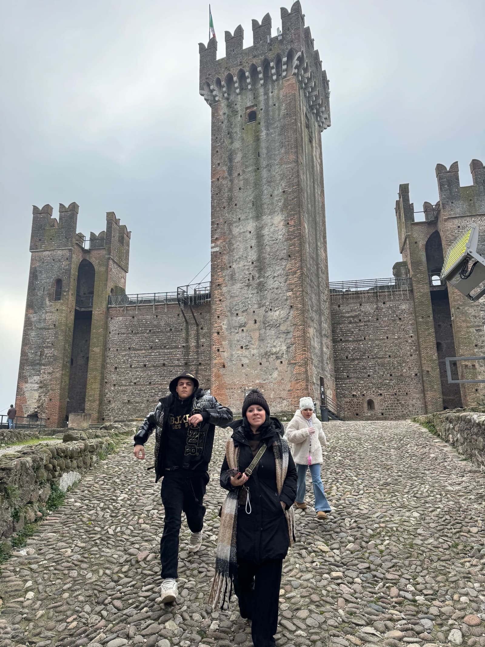 eccoci che scendiamo per la discesa acciottolata del Castello Scaligero, con la torre alle spalle