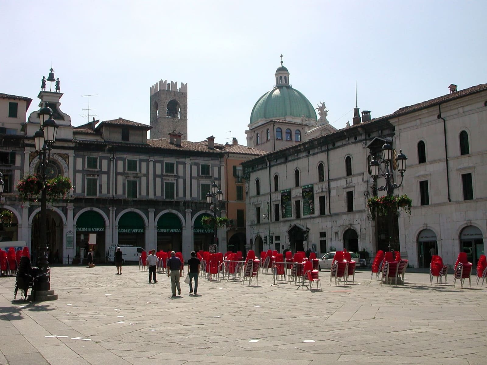 la Torre dell'Orologio sopra i portici di piazza della Loggia, con la torre del Broletto e la cupola del Duomo Nuovo dietro