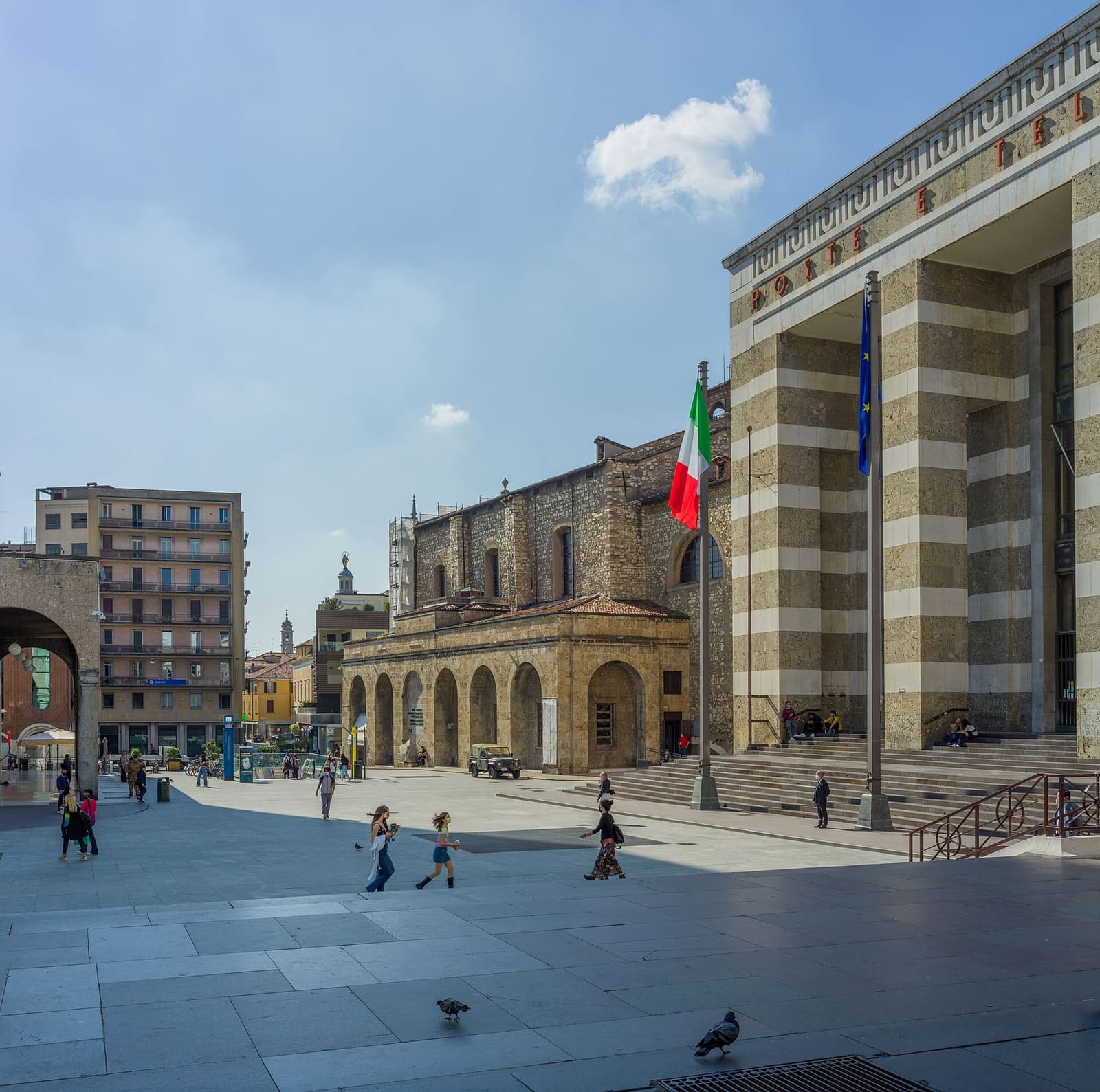 piazza della Vittoria con il Palazzo delle Poste a strisce bianche e ocra e l'arengario di pietra rossa