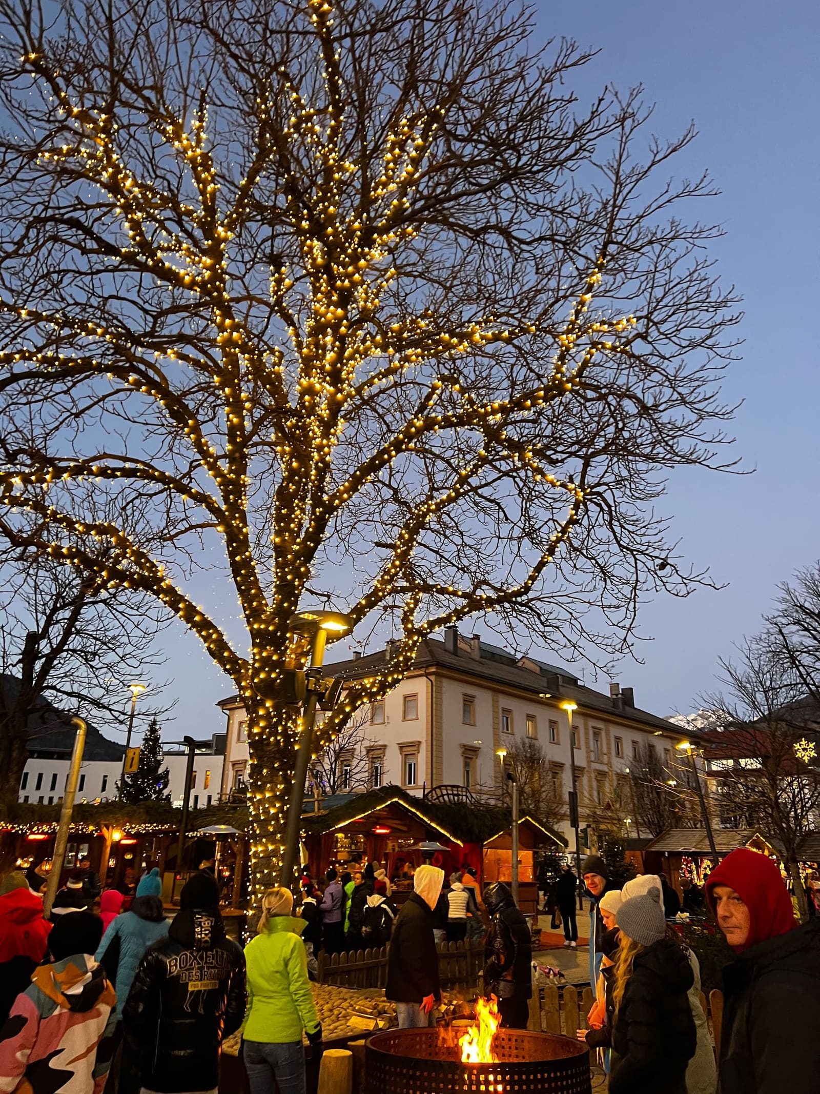 l'albero illuminato sopra le casette del mercatino, e il braciere attorno a cui ci si scalda