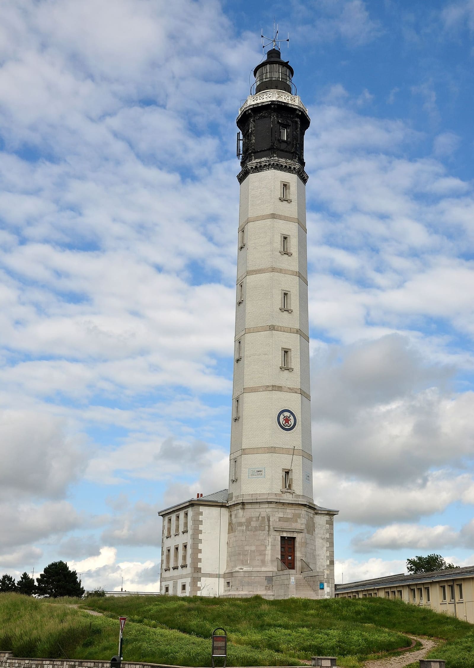 il faro di Calais, bianco con la lanterna nera, sotto un cielo di nuvole
