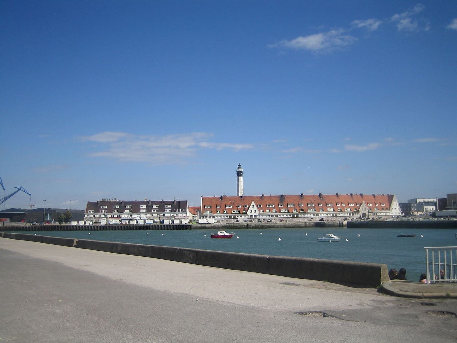 il faro sopra le case dai tetti rossi del Courgain maritime, oltre l'acqua del porto