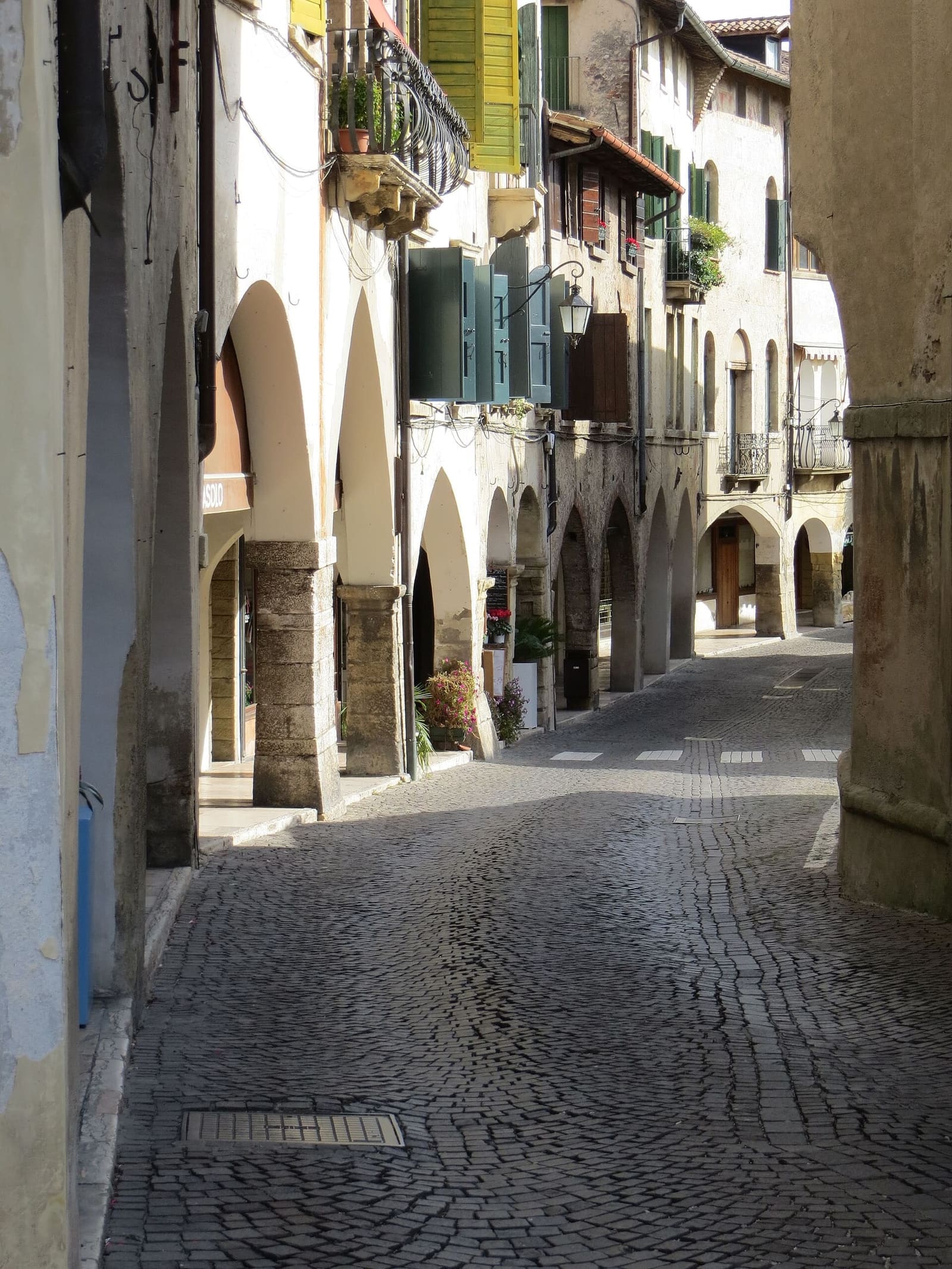 i portici di via Browning nel centro di Asolo, con le persiane verdi e il selciato
