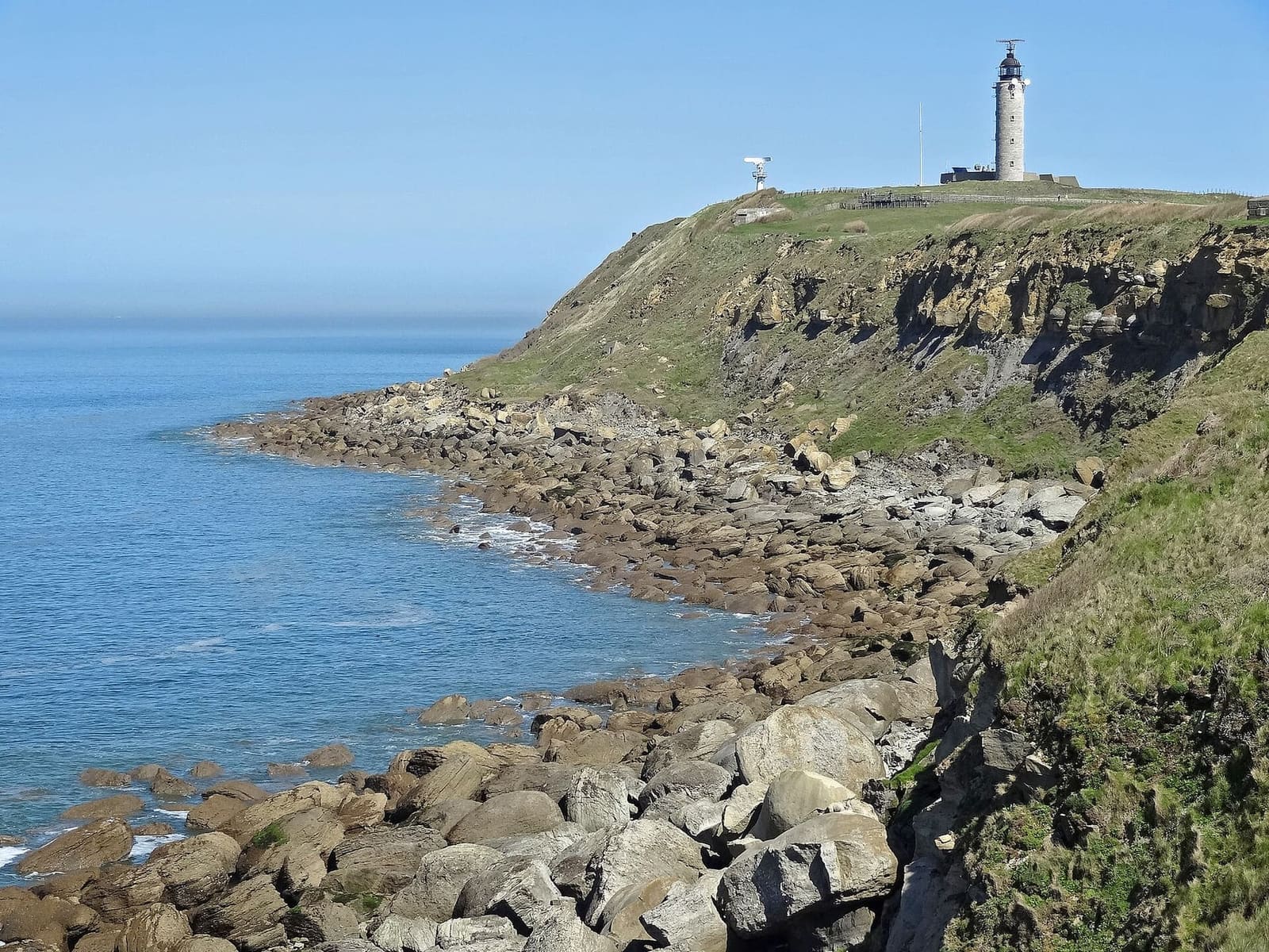 la punta del Gris-Nez con il faro sopra la falesia e i massi, sotto il cielo blu