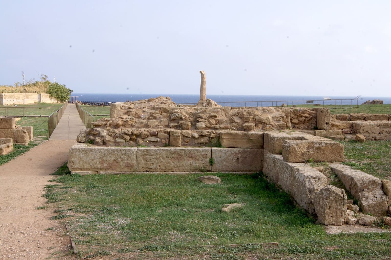 the remains of the sanctuary along the entrance path, with the column in the distance