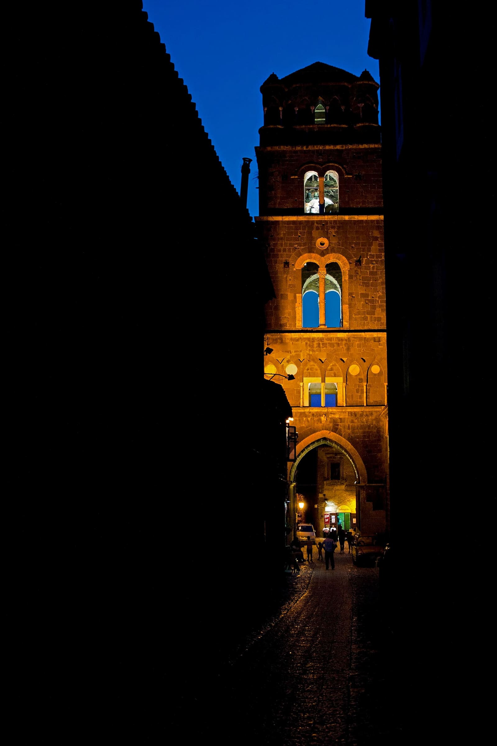 il campanile del Duomo illuminato la sera, in fondo a un vicolo di Casertavecchia