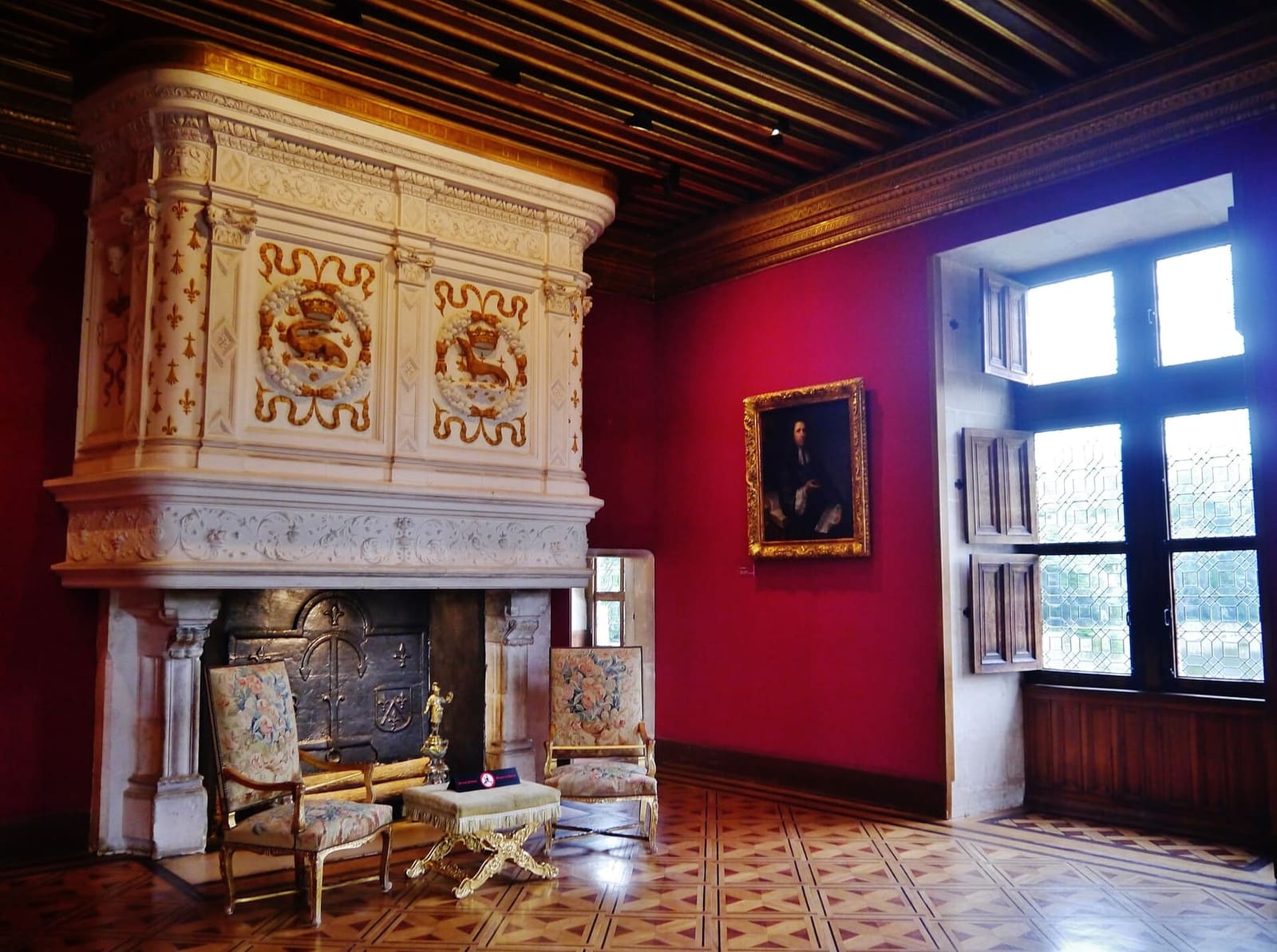 le salon Louis XIV, avec ses murs rouges et sa cheminée blanc et or