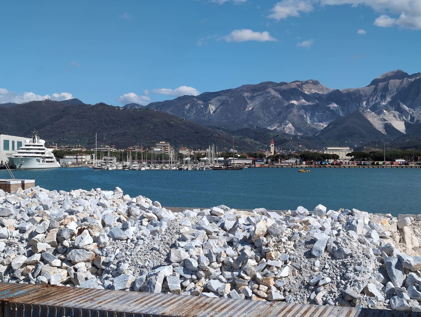 il porto di Marina di Carrara con i blocchi di marmo sulla banchina e le Apuane bianche dietro