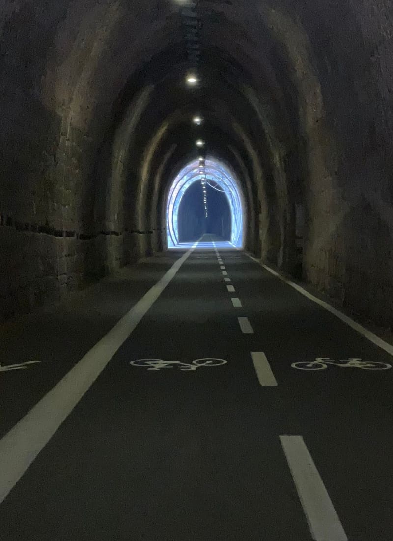 dentro una galleria ex ferroviaria, con le corsie segnate a terra e la luce in fondo