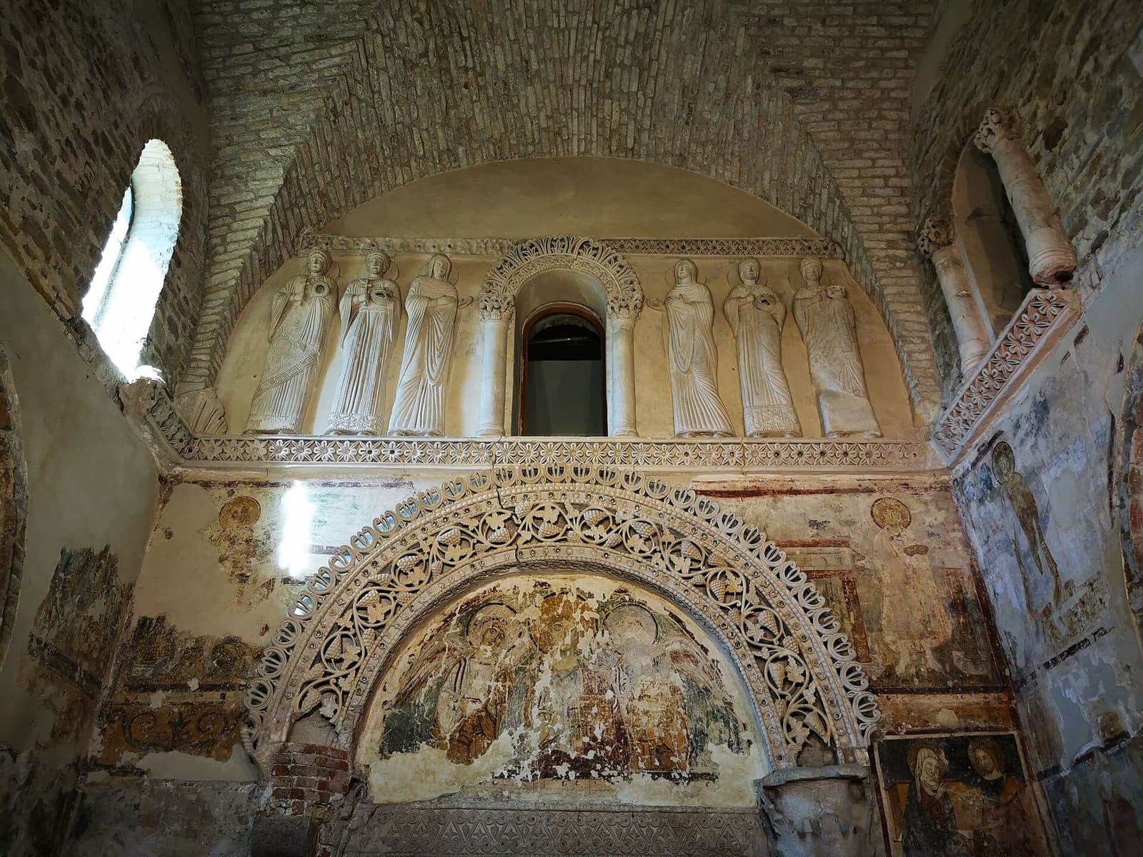 la parete d'ingresso del Tempietto longobardo, con le sante in stucco sopra l'arco decorato a tralci
