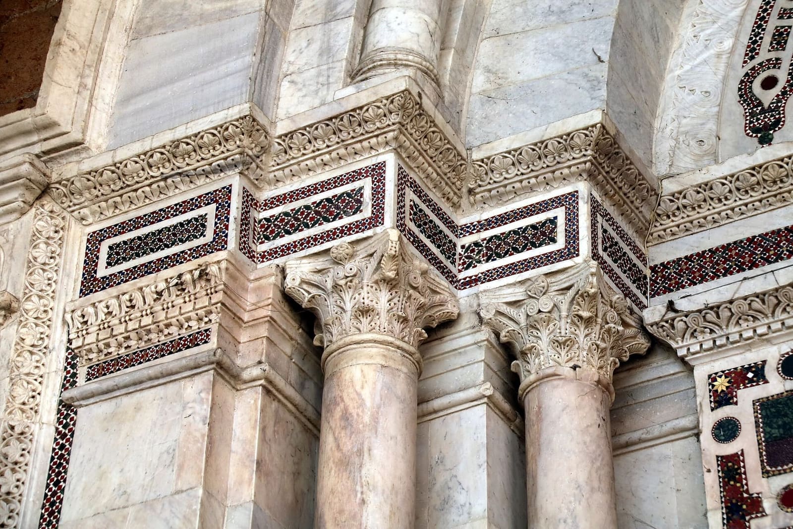 il fregio del portico da vicino, con le tessere rosse e verdi del mosaico cosmatesco fra i capitelli