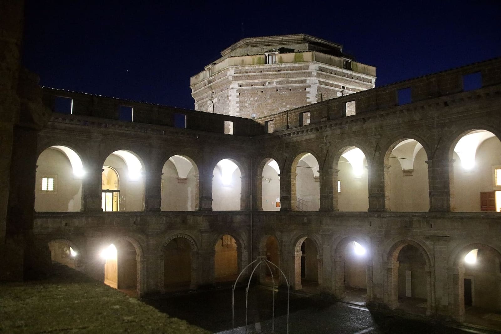 il cortile illuminato la sera, con il mastio ottagonale che spunta sopra le logge