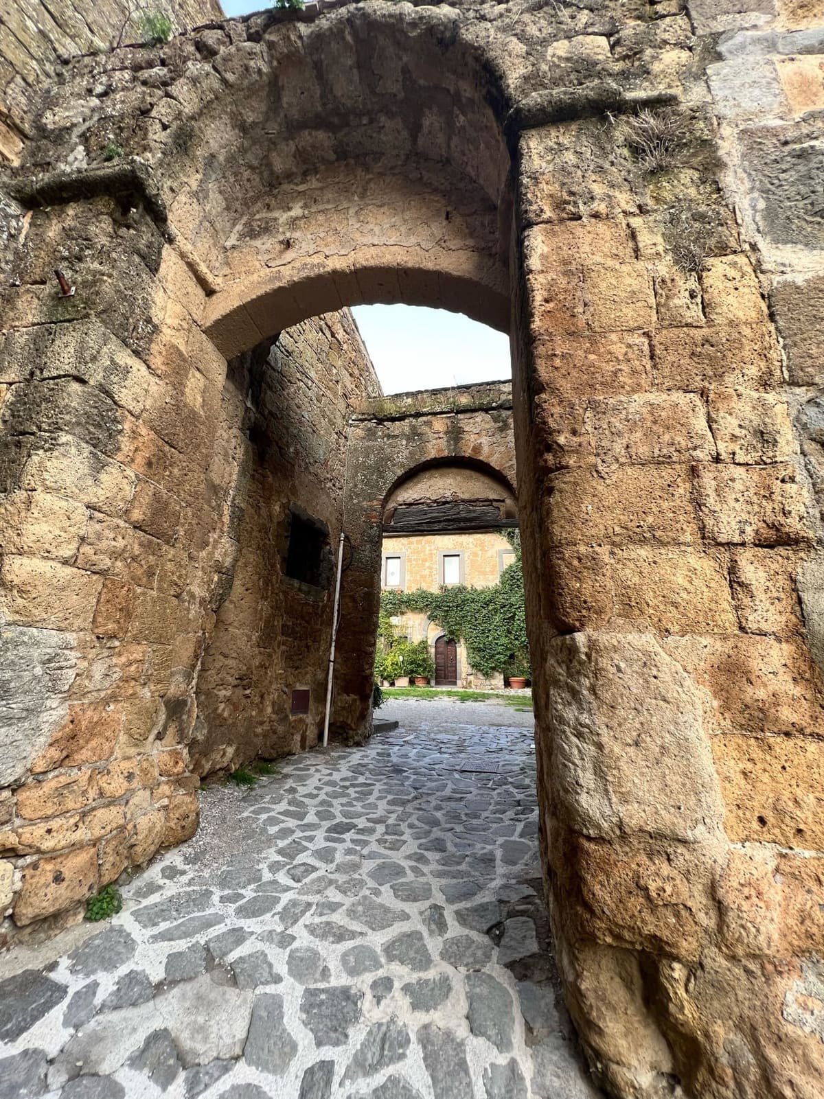 il passaggio a doppio arco scavato nel tufo, aperto su una corte con la casa coperta d'edera