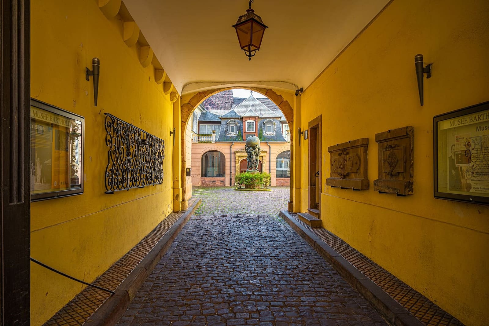 l'androne giallo che porta al cortile del museo Bartholdi, con il gruppo di bronzo in fondo