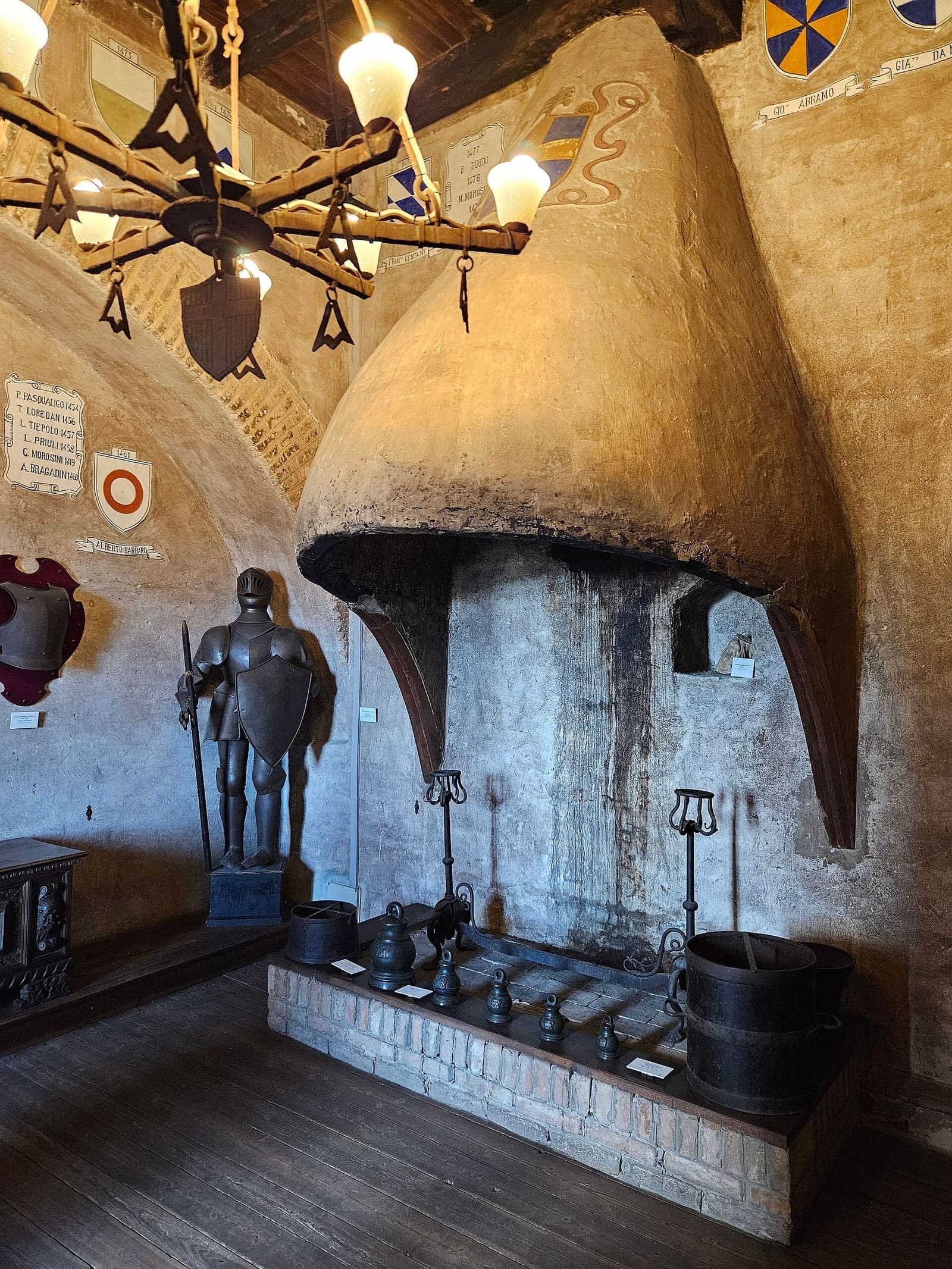 der große Kamin und eine Rüstung in einem Saal des Museo civico der Burg