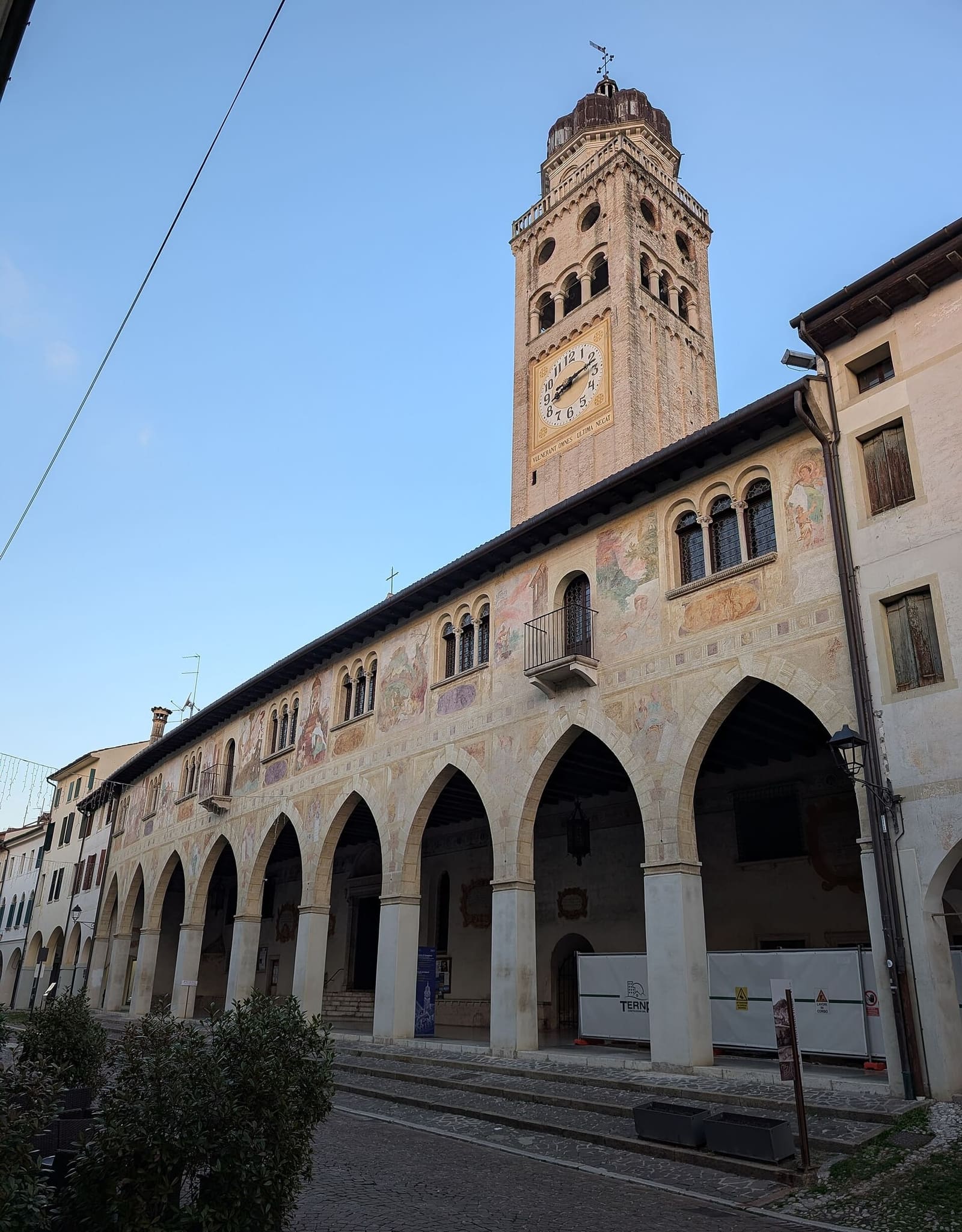 die freskierte Fassade der Scuola dei Battuti über dem Laubengang des Doms, mit dem Glockenturm