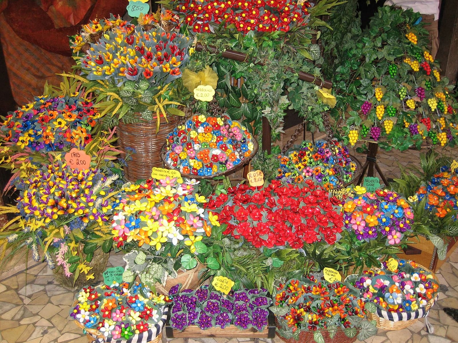 flowers, bunches of grapes and bouquets of coloured confetti on display in front of a shop in Sulmona