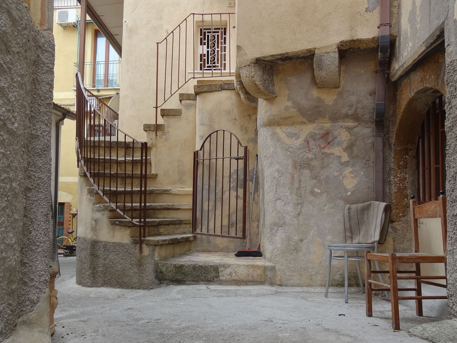 un cortile del centro storico, con la scala di pietra e due sedie