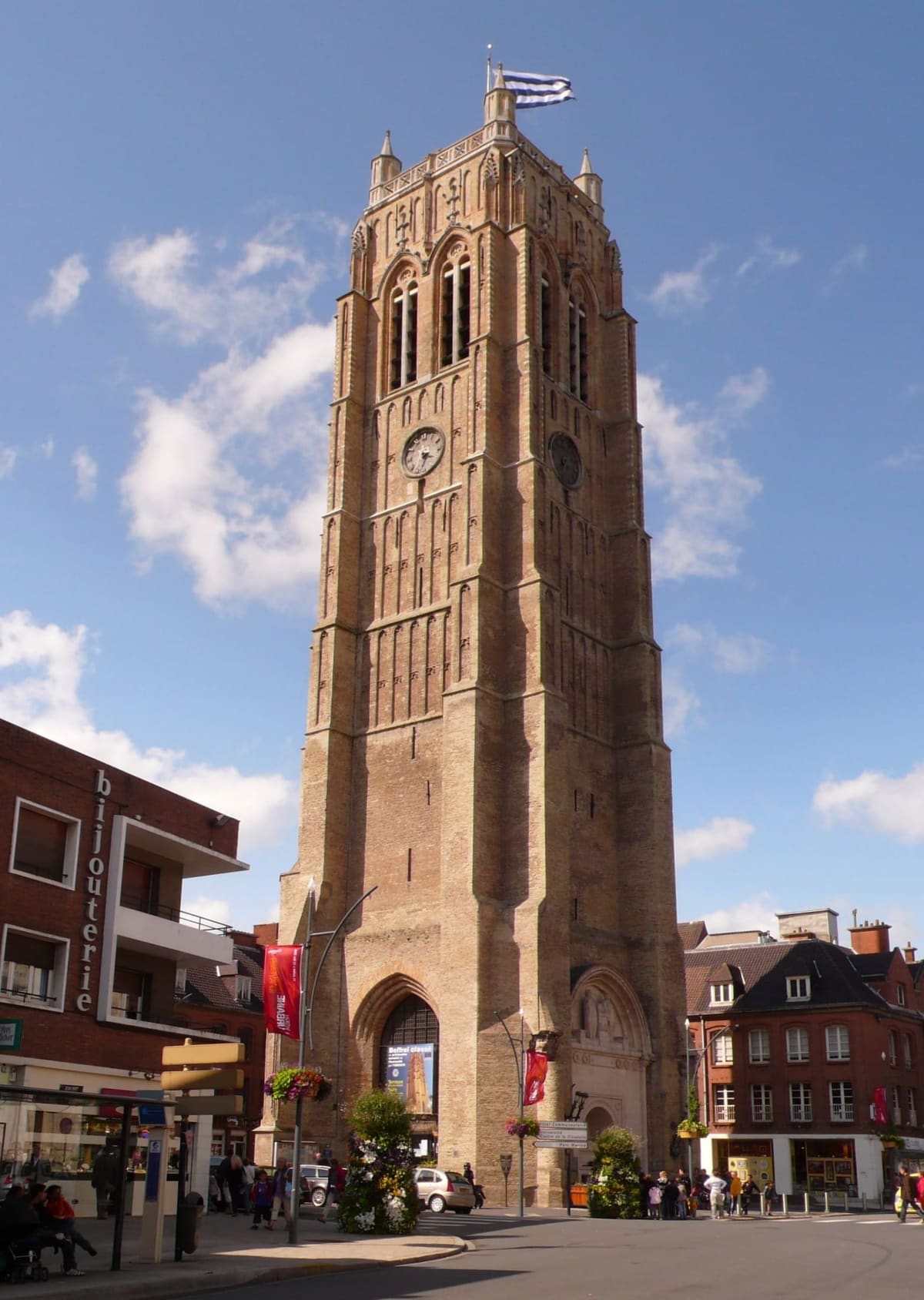 the Saint-Éloi belfry, the 58-metre brick tower, under a blue sky with clouds