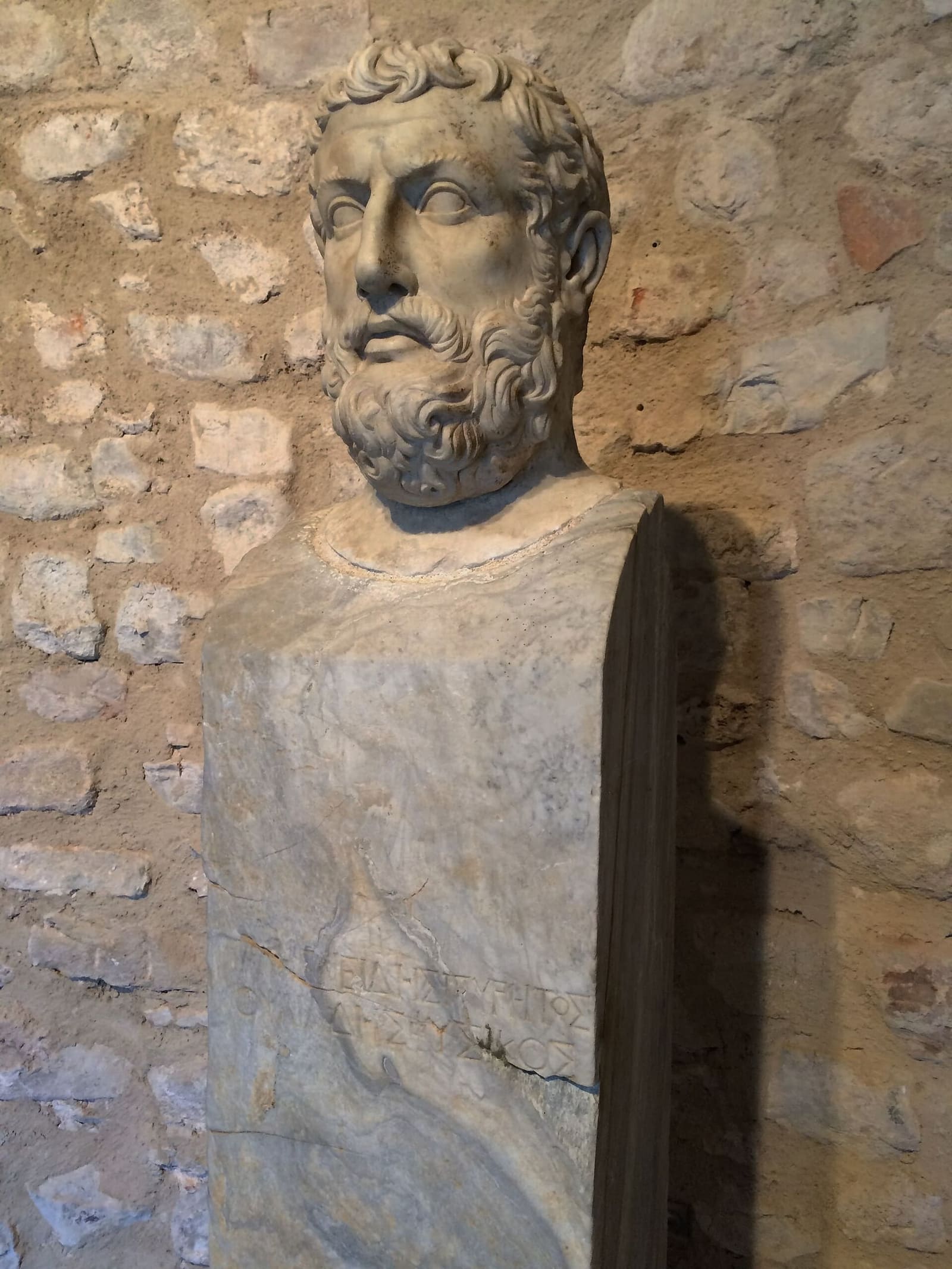 il busto di Parmenide, di marmo, contro il muro di pietra