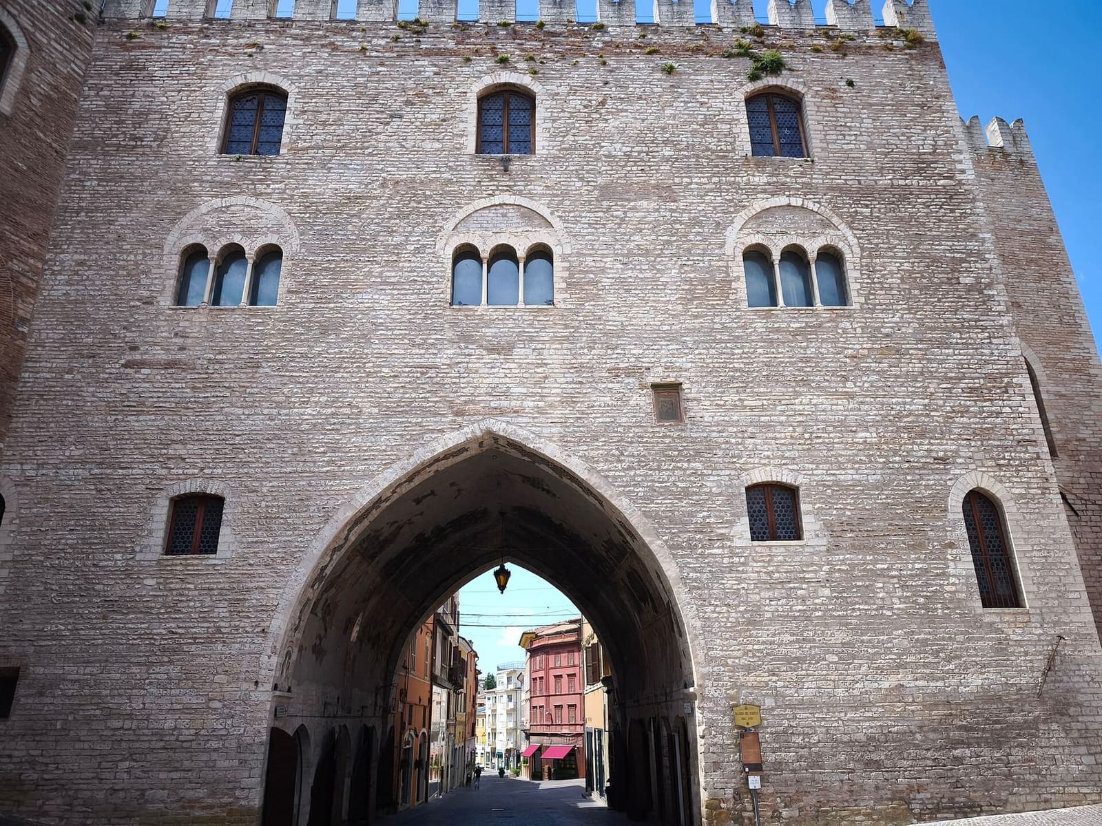la facciata merlata del Palazzo del Podestà, con le trifore e il grande arco a sesto acuto che scavalca la strada