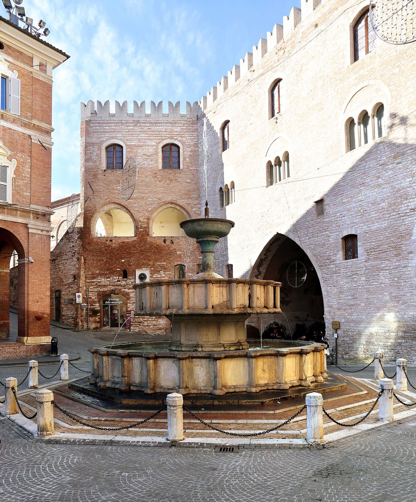 la fontana Sturinalto, del 1285, con le tre vasche sovrapposte, e dietro i merli e l'arco del Palazzo del Podestà