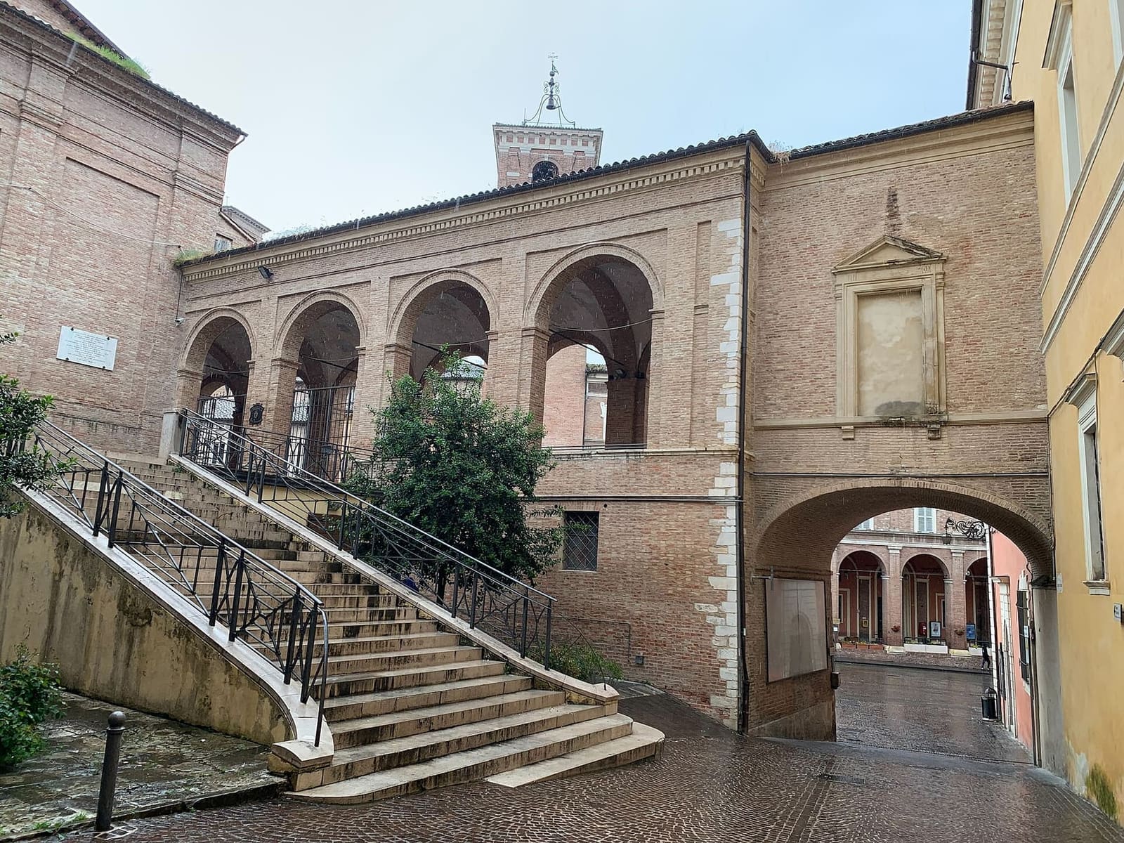 la scalinata che sale al loggiato di San Francesco, con l'arco che passa sotto e in fondo i portici della piazza