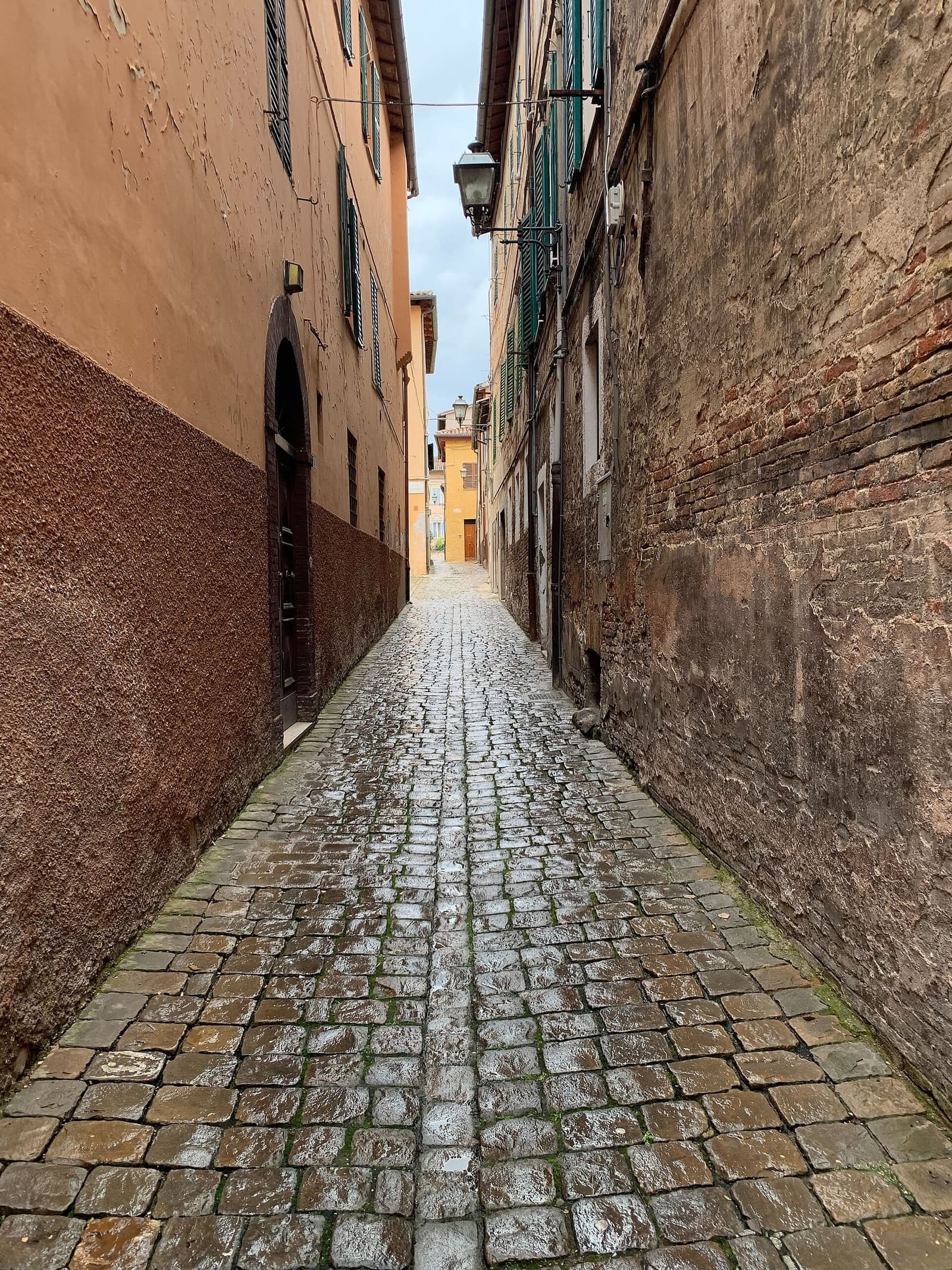 un vicolo lastricato del centro storico, stretto fra muri di mattoni e intonaco