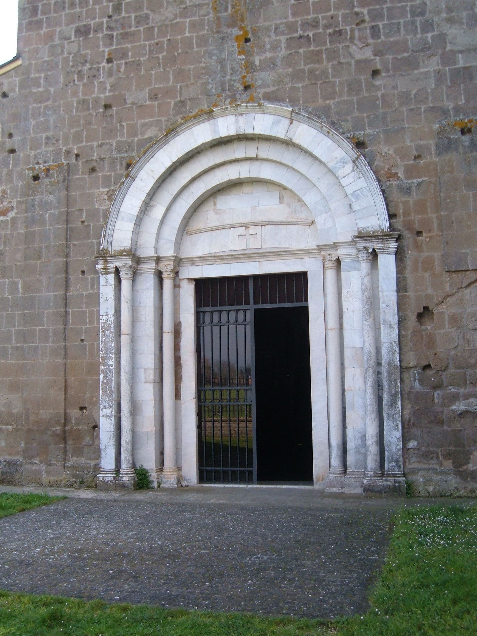 il portale dei Cosmati: le colonnine e le ghiere di marmo bianco, a tutto sesto, incastrate nella facciata di tufo