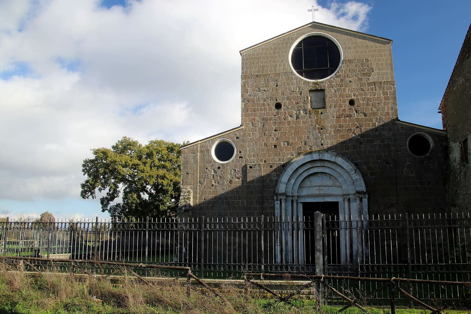 la facciata dell'abbazia, nuda e a capanna, con il grande rosone, i due oculi e il portale di marmo bianco in mezzo